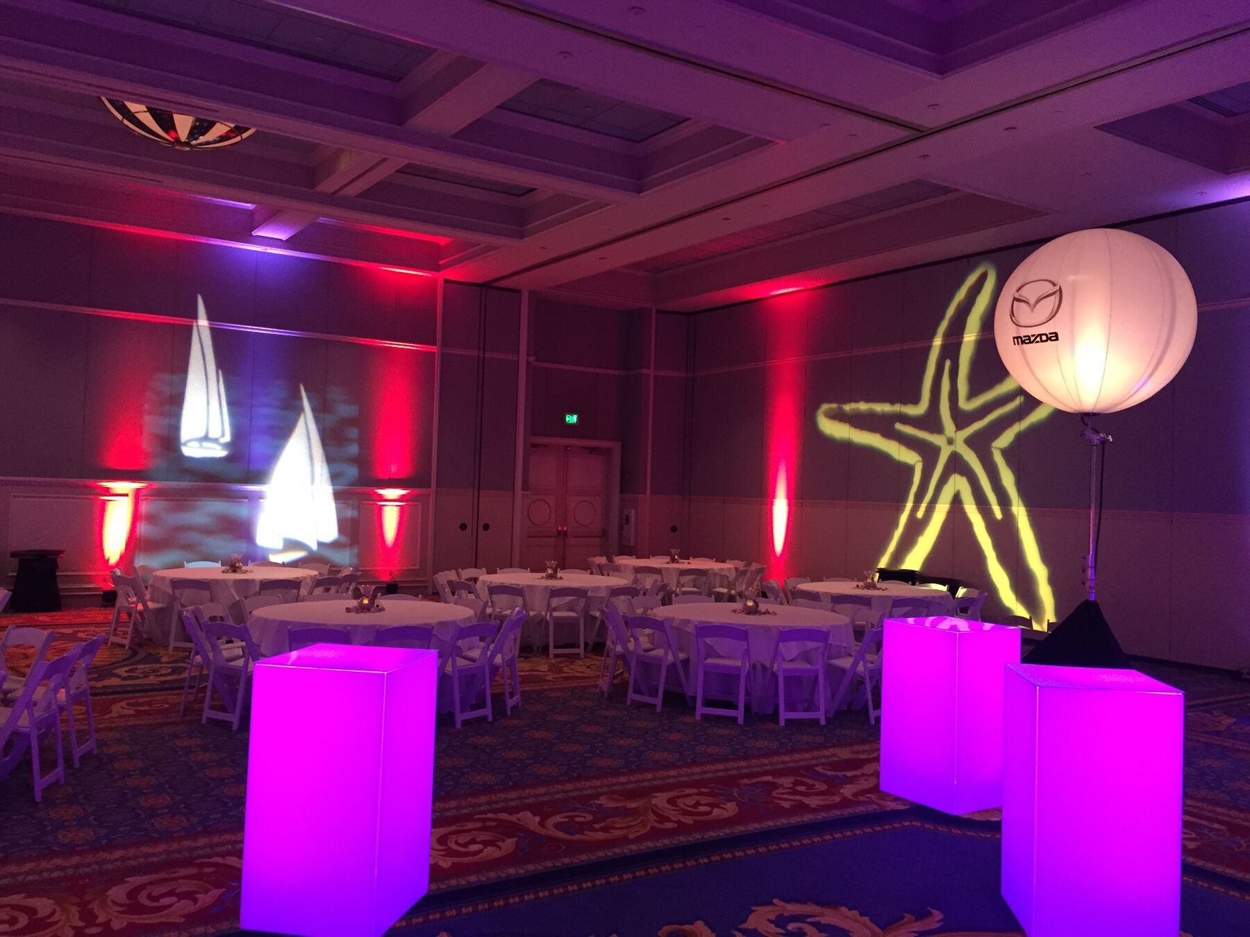 Themed ballroom with red uplighting, glowing cocktail tables and custom gobo projections