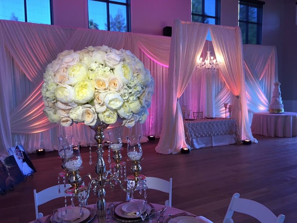 Pink uplighting on ivory draping behind a sweetheart table